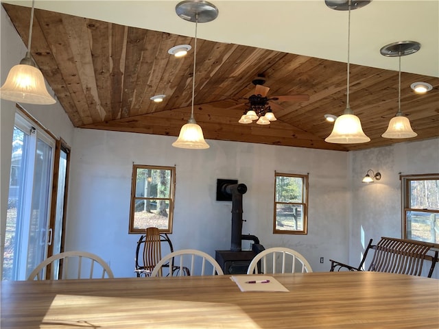 dining area with wooden ceiling, a wood stove, a wealth of natural light, and lofted ceiling