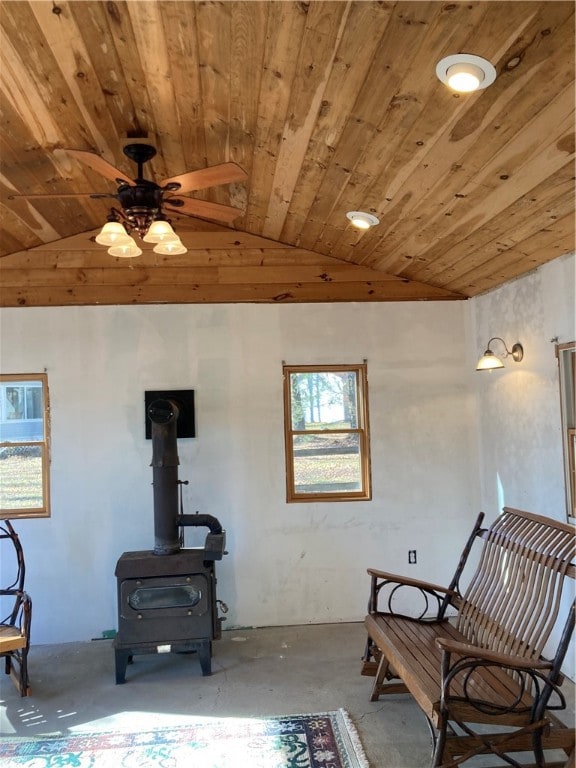 living area with lofted ceiling, ceiling fan, a wood stove, and wood ceiling