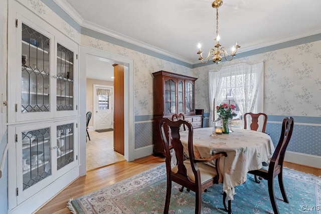 dining area featuring plenty of natural light, crown molding, an inviting chandelier, and light wood-type flooring