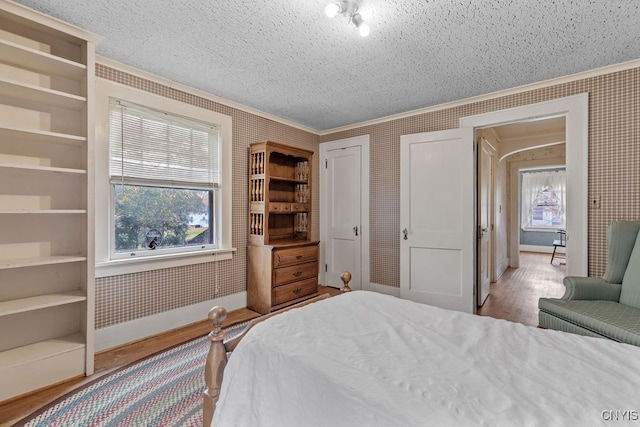 bedroom featuring a textured ceiling, multiple windows, and light hardwood / wood-style floors