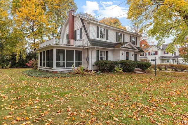 back of house featuring a lawn and a sunroom