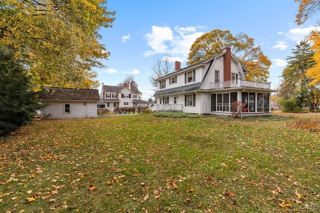 rear view of house featuring a yard and a sunroom