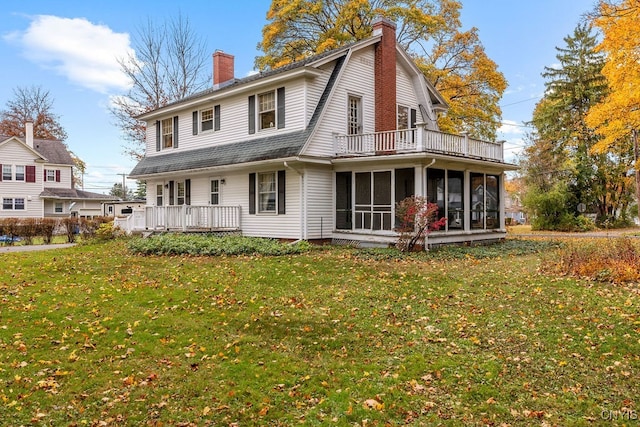 rear view of property with a wooden deck, a sunroom, and a lawn