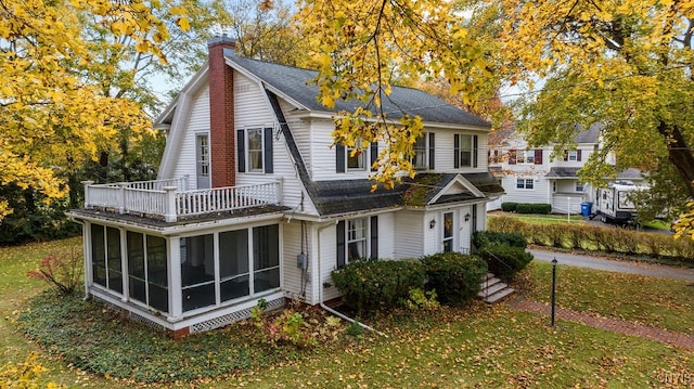 back of property with a balcony, a lawn, and a sunroom