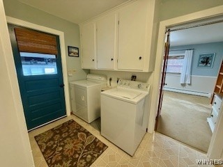 clothes washing area with baseboard heating, washer and clothes dryer, and cabinets