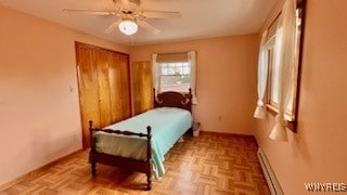 bedroom featuring a closet, light parquet floors, a baseboard heating unit, and ceiling fan