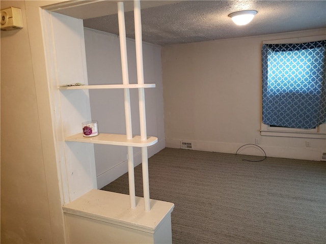 carpeted empty room featuring a textured ceiling