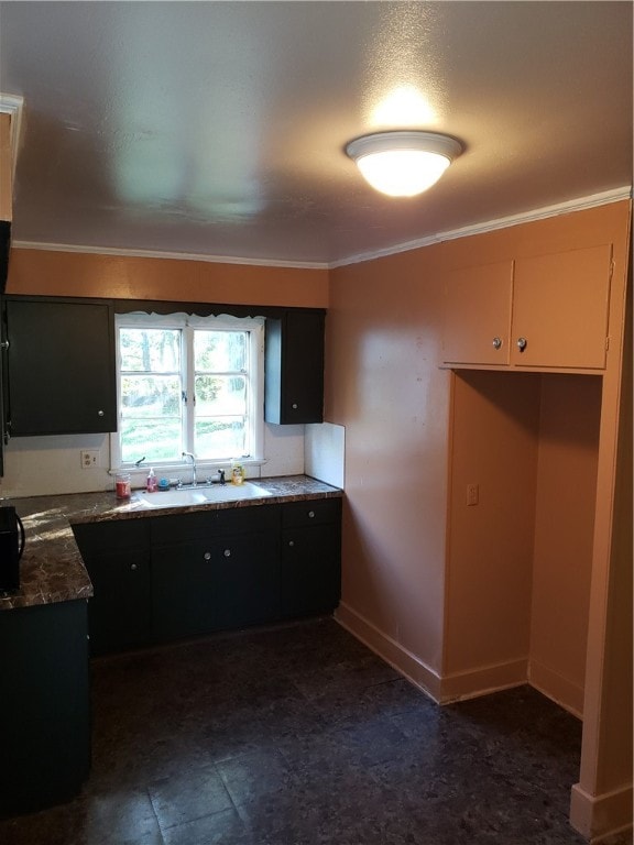 kitchen featuring ornamental molding, sink, and dark stone counters