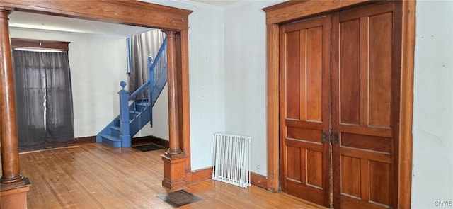 entrance foyer with decorative columns, ornamental molding, and light wood-type flooring