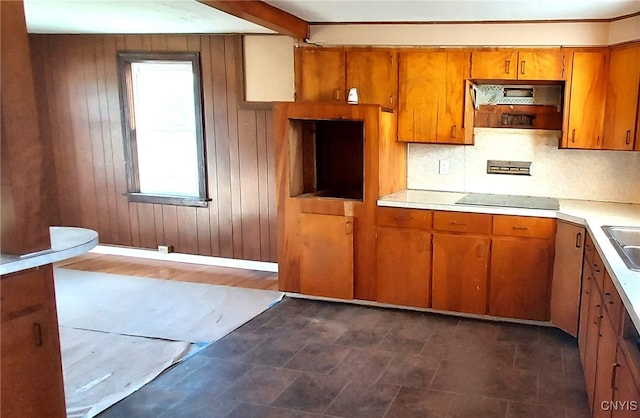 kitchen featuring black electric cooktop, decorative backsplash, wooden walls, and sink