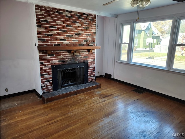 unfurnished living room featuring ceiling fan, a fireplace, and dark hardwood / wood-style flooring