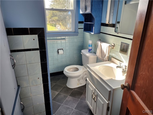 bathroom with tile walls, vanity, toilet, and tile patterned floors