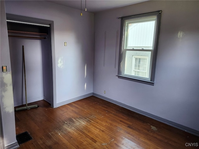 unfurnished bedroom with a closet and dark hardwood / wood-style floors