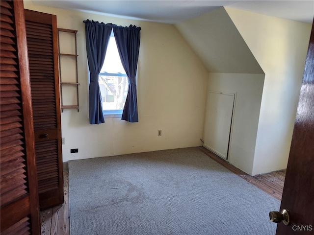 additional living space with hardwood / wood-style flooring and vaulted ceiling