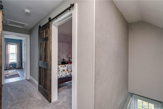 hallway featuring visible vents, carpet, and a wealth of natural light