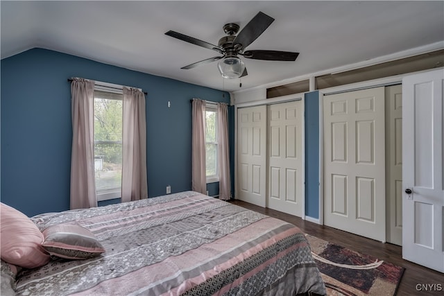 bedroom with ceiling fan, vaulted ceiling, two closets, and dark hardwood / wood-style flooring