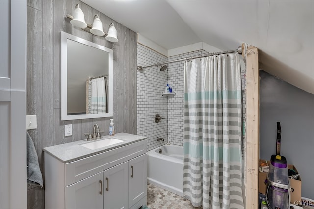 bathroom featuring vanity, shower / bathtub combination with curtain, and vaulted ceiling