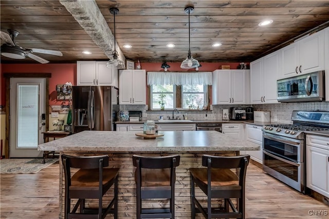 kitchen with white cabinets, a kitchen breakfast bar, a center island, stainless steel appliances, and wood ceiling