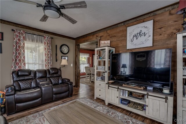 living room featuring ceiling fan, hardwood / wood-style flooring, crown molding, and wooden walls