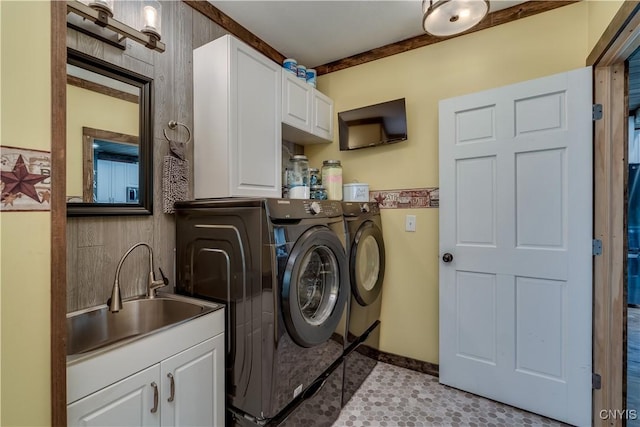 laundry area featuring cabinet space, separate washer and dryer, baseboards, and a sink