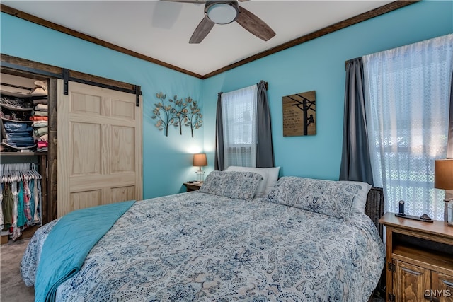 bedroom with a closet, ceiling fan, crown molding, and a barn door