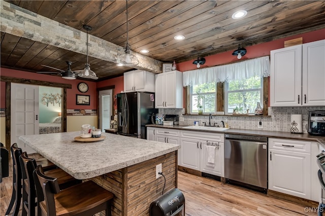 kitchen featuring appliances with stainless steel finishes, sink, light hardwood / wood-style floors, pendant lighting, and white cabinets