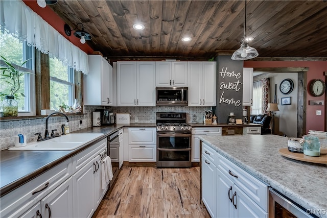 kitchen with hanging light fixtures, stainless steel appliances, sink, light wood-type flooring, and white cabinetry