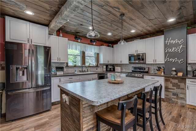 kitchen featuring light hardwood / wood-style flooring, white cabinetry, stainless steel appliances, and pendant lighting