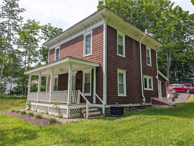 view of front facade featuring central AC, covered porch, and a front lawn