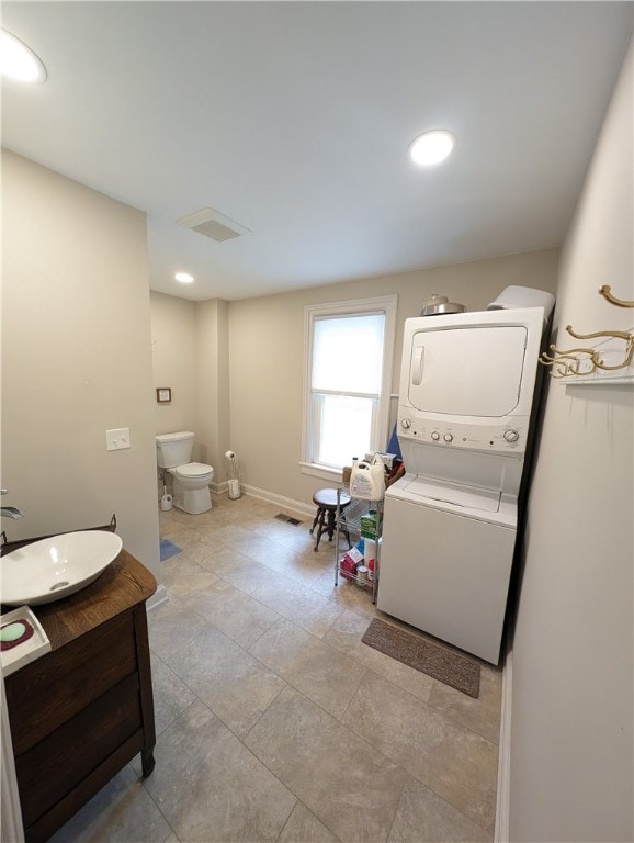 bathroom featuring vanity, stacked washer and dryer, and toilet