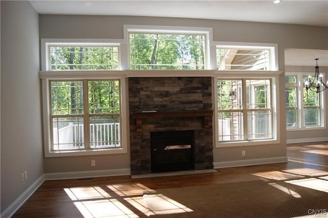 1015 Cold Springs Rd, Salina, NY 13088 - unfurnished living room featuring a stone fireplace, an inviting chandelier, and dark hardwood / wood-style flooring