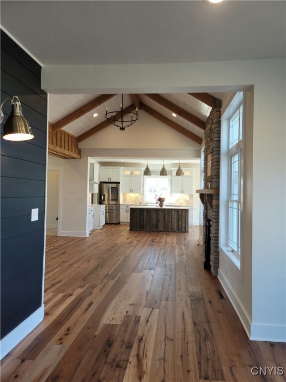 1015 Cold Springs Rd, Salina, NY 13088 - unfurnished living room with hardwood / wood-style floors, vaulted ceiling with beams, and a stone fireplace