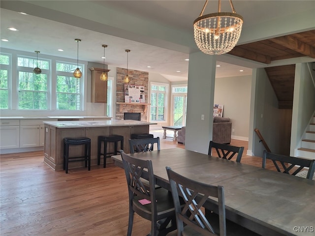 1015 Cold Springs Rd, Salina, NY 13088 - dining room featuring light hardwood / wood-style flooring, beam ceiling, a chandelier, and a fireplace