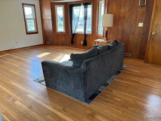 living room featuring a healthy amount of sunlight, wooden walls, and light hardwood / wood-style floors