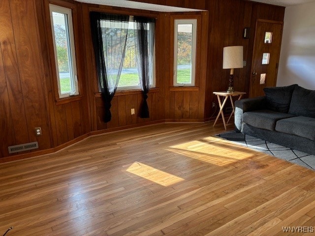 living room with light hardwood / wood-style flooring and wooden walls