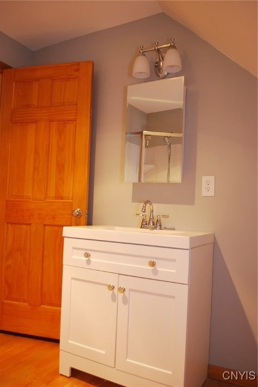 bathroom with vanity, lofted ceiling, and wood-type flooring