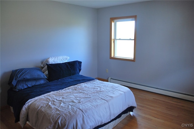 bedroom with baseboard heating and hardwood / wood-style flooring