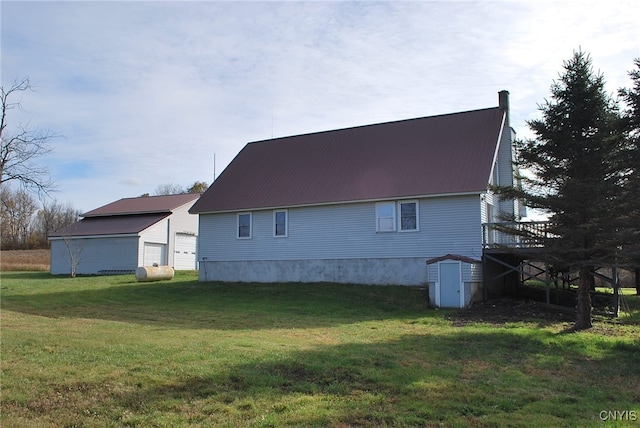 view of property exterior featuring a wooden deck, a lawn, and an outdoor structure