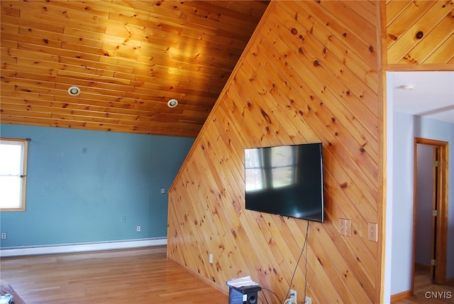 unfurnished living room featuring lofted ceiling, a baseboard radiator, wooden ceiling, light wood-type flooring, and wooden walls