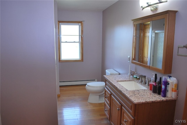 bathroom with toilet, a baseboard heating unit, hardwood / wood-style flooring, and vanity