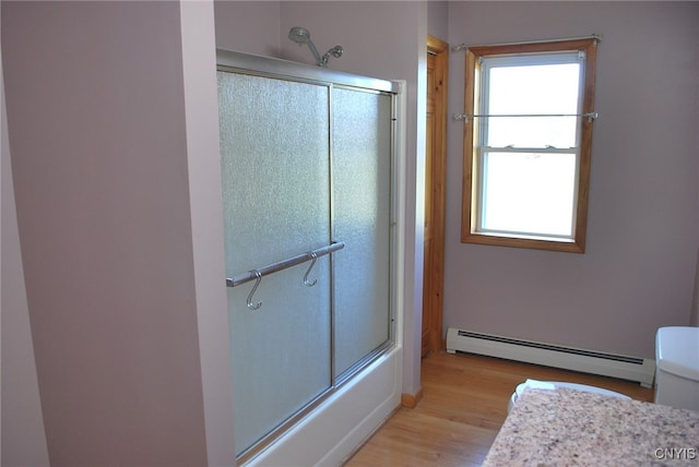 bathroom featuring baseboard heating, hardwood / wood-style floors, a healthy amount of sunlight, and toilet