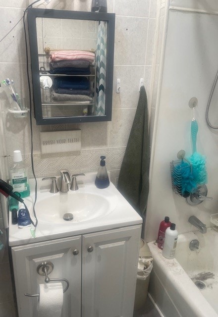 bathroom featuring vanity, tasteful backsplash, shower / bath combo with shower curtain, and tile walls