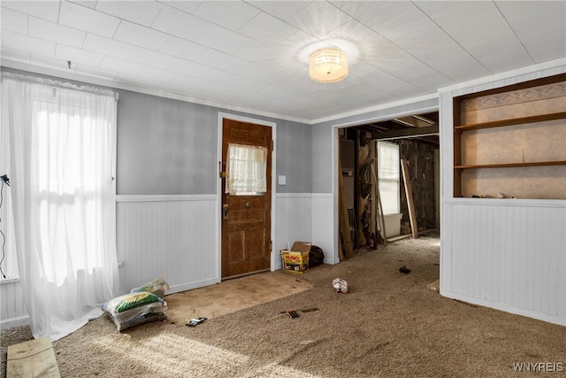 interior space with ornamental molding, carpet, and wooden walls