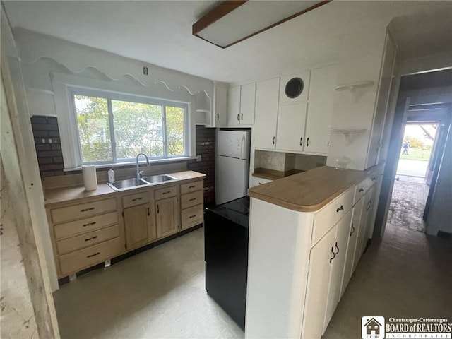 kitchen featuring white cabinets, sink, light brown cabinetry, and white refrigerator