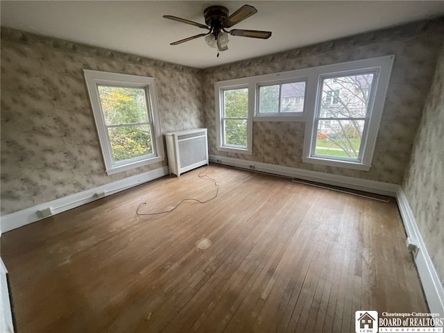 interior space with ceiling fan, radiator heating unit, and light wood-type flooring