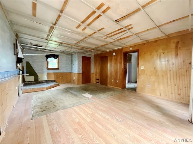 basement with light hardwood / wood-style flooring and wooden walls