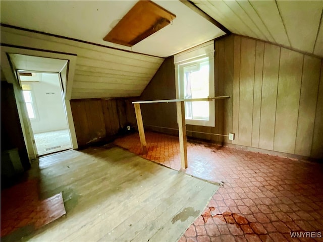 additional living space with lofted ceiling, hardwood / wood-style floors, and wood walls