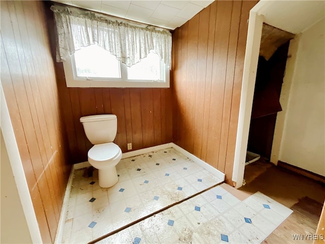 bathroom with toilet and wood walls