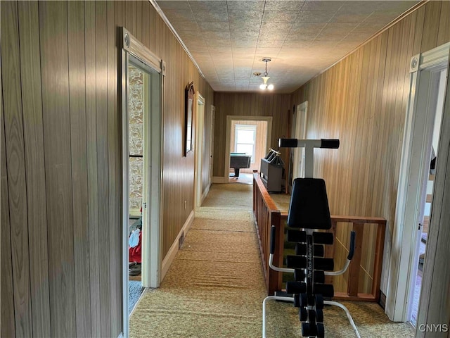 hall featuring light carpet and wood walls