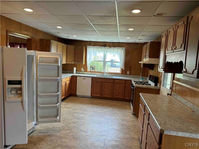 kitchen featuring wood walls, sink, a paneled ceiling, and white appliances